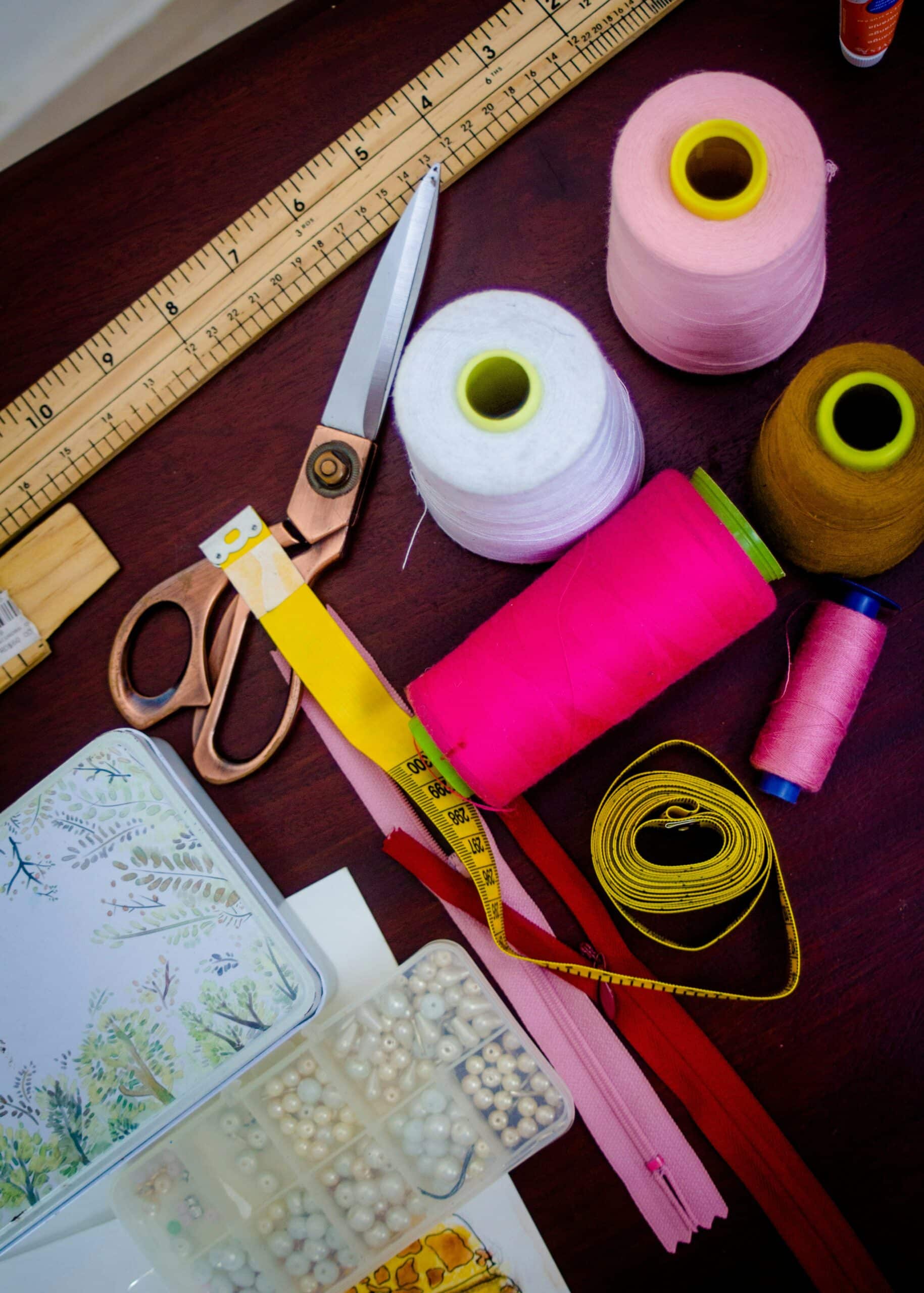 Outils de couture : ciseaux, règle graduée, mètre ruban, bobines de fil et fermetures éclair
